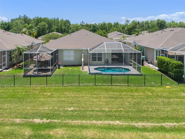 back of house featuring a patio, glass enclosure, a lawn, and a fenced in pool