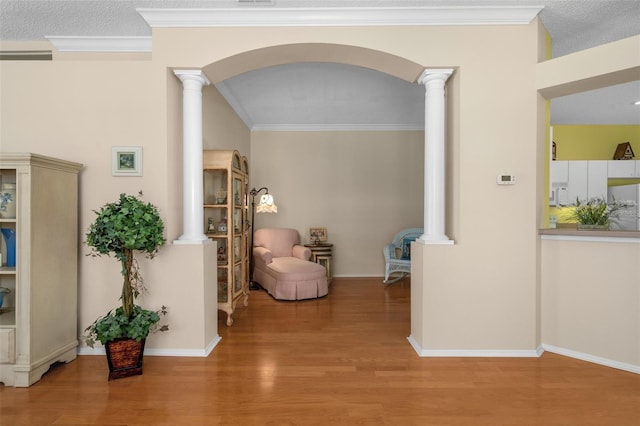 sitting room with wood-type flooring, ornate columns, and ornamental molding