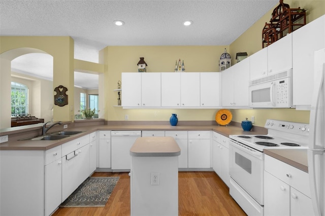 kitchen featuring a center island, sink, white appliances, and white cabinets