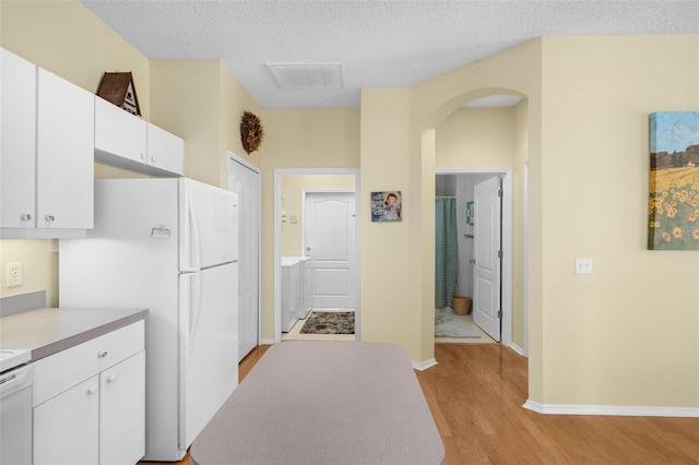 kitchen featuring light hardwood / wood-style flooring, white cabinetry, white refrigerator, and a textured ceiling