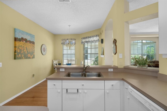 kitchen with sink, white cabinets, white dishwasher, and decorative light fixtures