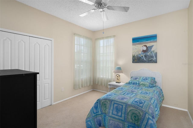 bedroom with a closet, ceiling fan, carpet floors, and a textured ceiling