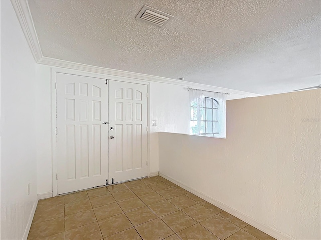 unfurnished room featuring light tile patterned floors, crown molding, and a textured ceiling