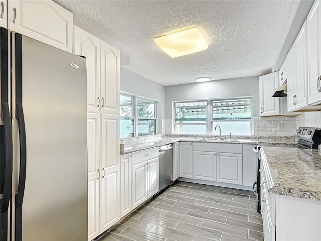 kitchen with stainless steel appliances, white cabinetry, sink, and backsplash