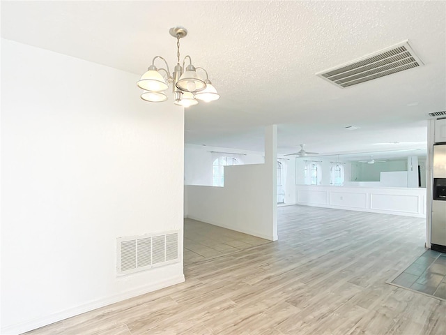 unfurnished room with ceiling fan with notable chandelier, light hardwood / wood-style floors, and a textured ceiling