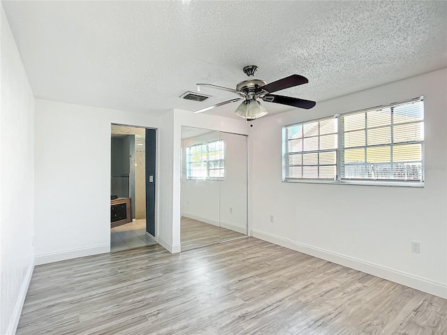 spare room featuring ceiling fan, light hardwood / wood-style flooring, and a textured ceiling