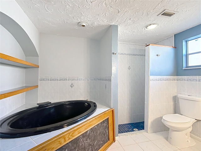 bathroom featuring tile patterned floors, toilet, separate shower and tub, tile walls, and a textured ceiling