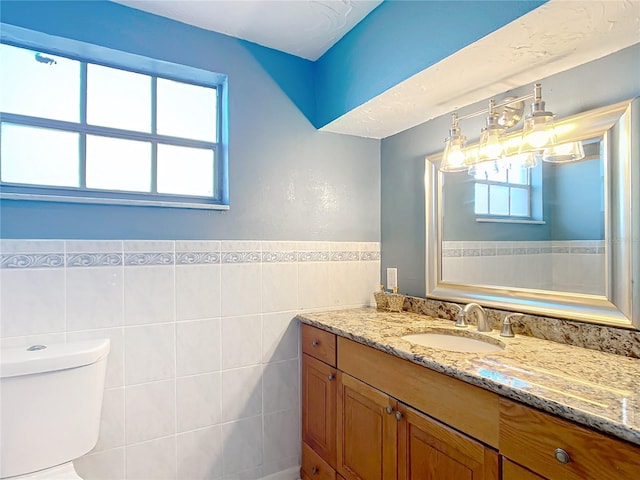 bathroom with vanity, toilet, and tile walls