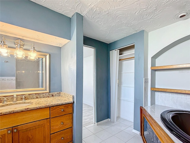 bathroom featuring vanity, a tub, tile patterned floors, and a textured ceiling