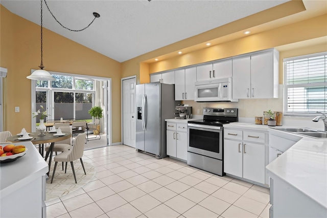 kitchen featuring stainless steel appliances, light tile patterned flooring, white cabinets, and decorative light fixtures