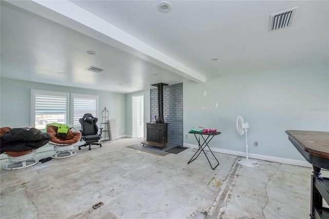 living room featuring a wood stove and beam ceiling