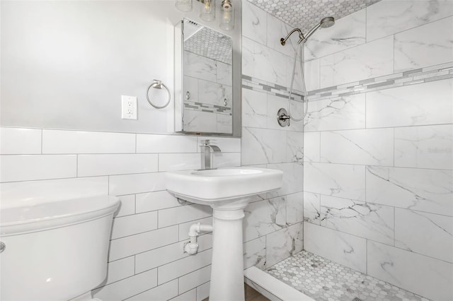 bathroom featuring a tile shower, tile walls, and toilet