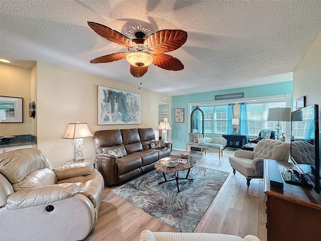 living area featuring wood-type flooring, ceiling fan, and a textured ceiling