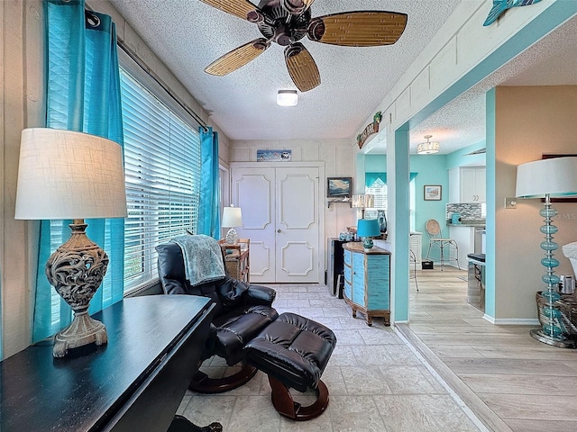 office with light wood-type flooring, ceiling fan, a textured ceiling, and baseboards