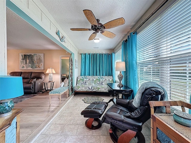 living area with a textured ceiling and a ceiling fan