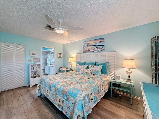 bedroom featuring a textured ceiling, wood finished floors, visible vents, and a ceiling fan