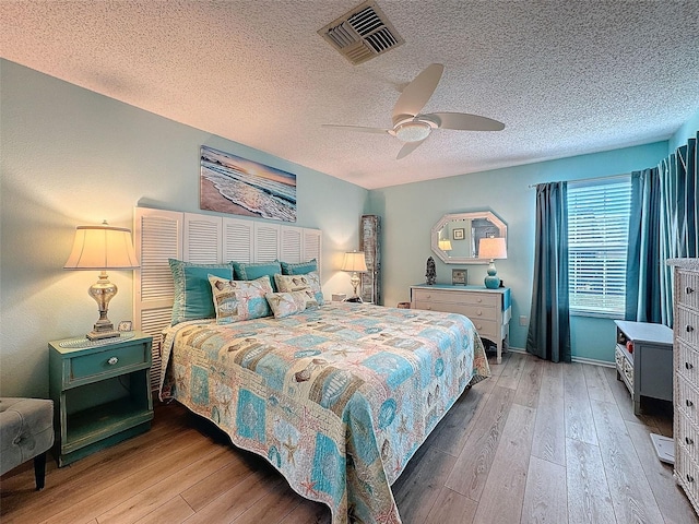 bedroom with visible vents, ceiling fan, a textured ceiling, and wood finished floors