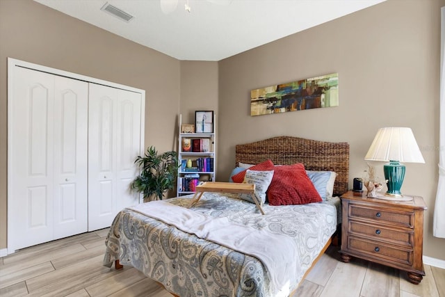 bedroom with a ceiling fan, wood tiled floor, visible vents, and a closet