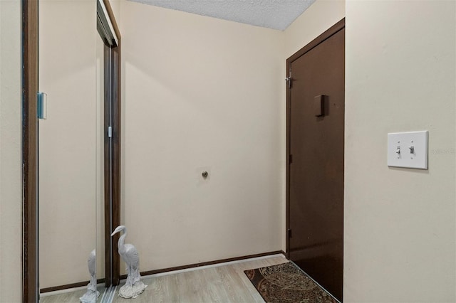 hall with light hardwood / wood-style floors and a textured ceiling