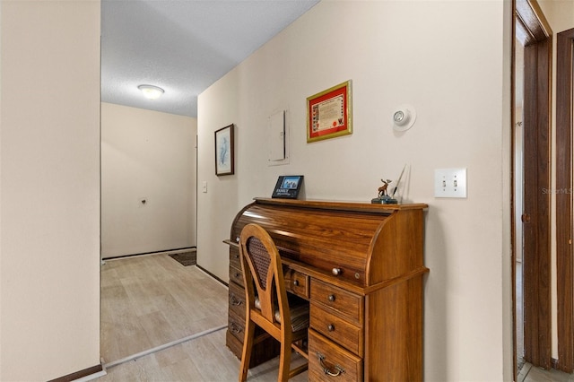 home office featuring light hardwood / wood-style flooring and a textured ceiling