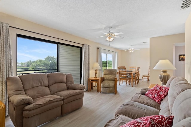 living room featuring ceiling fan, a textured ceiling, and light hardwood / wood-style flooring