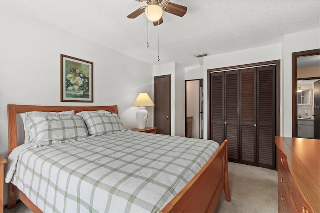 carpeted bedroom featuring ceiling fan, a textured ceiling, and multiple closets