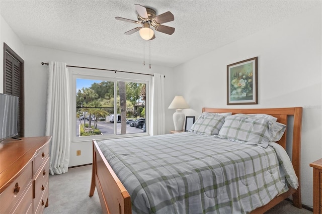 bedroom with ceiling fan, light colored carpet, and a textured ceiling