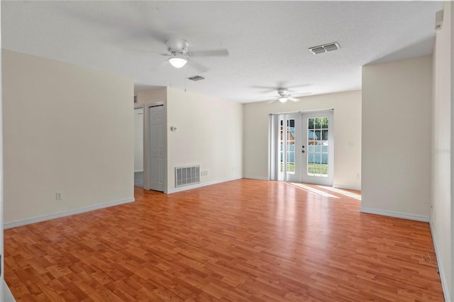 empty room with a textured ceiling, french doors, ceiling fan, and light hardwood / wood-style flooring