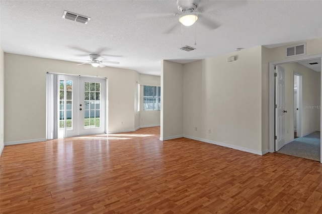 unfurnished room featuring a textured ceiling, french doors, hardwood / wood-style floors, and ceiling fan