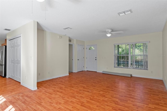 spare room featuring ceiling fan, light hardwood / wood-style floors, and a textured ceiling