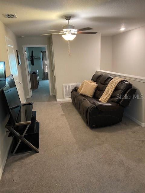 carpeted living room with ceiling fan