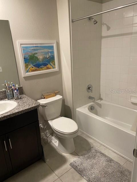 full bathroom featuring tile patterned flooring, tiled shower / bath, vanity, and toilet