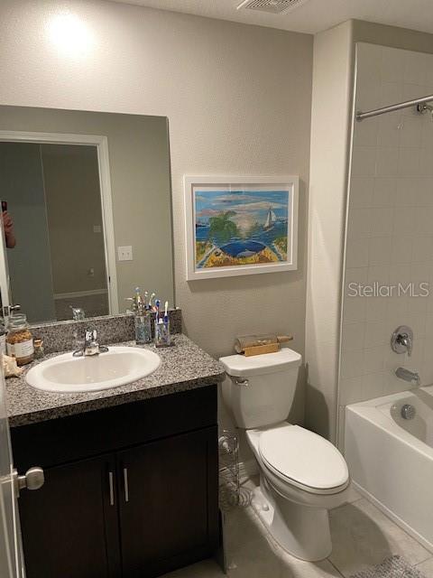 full bathroom featuring tile patterned flooring, vanity, toilet, and tiled shower / bath