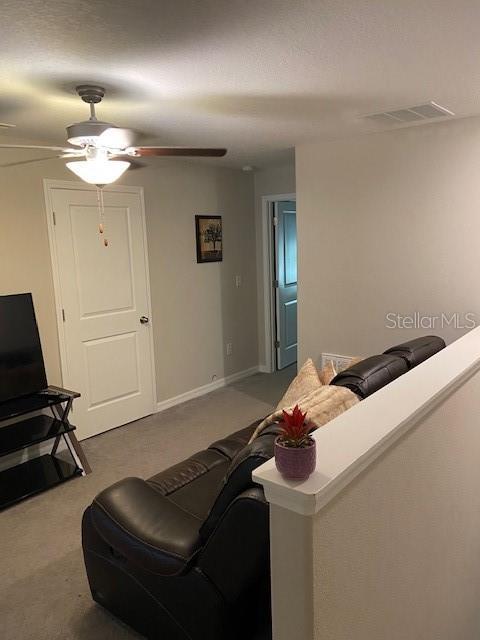 carpeted living room featuring ceiling fan