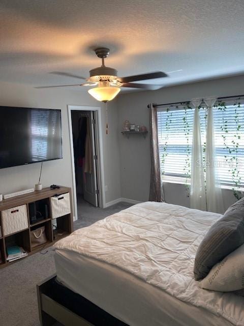 carpeted bedroom featuring ceiling fan and a textured ceiling