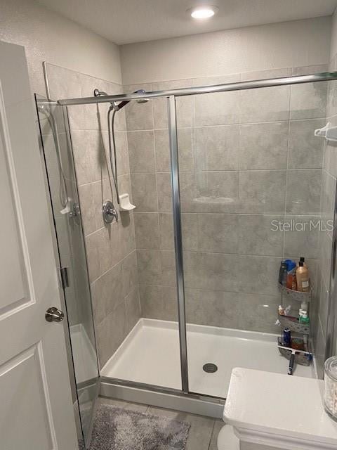 bathroom with tile patterned floors and a shower with door