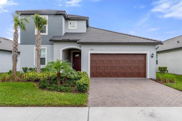 view of front of house with stucco siding, an attached garage, a tile roof, and decorative driveway