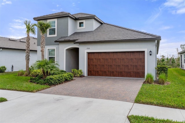 view of front facade featuring a tiled roof, decorative driveway, a garage, and stucco siding