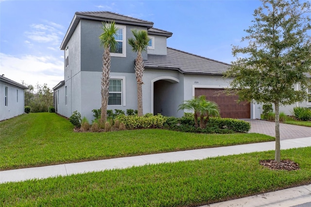 view of front of property featuring stucco siding, decorative driveway, a front yard, an attached garage, and a tiled roof