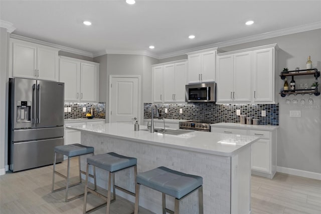 kitchen featuring white cabinets, appliances with stainless steel finishes, a kitchen breakfast bar, and a sink