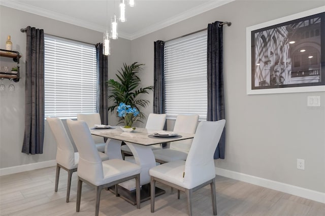 dining space featuring baseboards, light wood-style floors, and crown molding