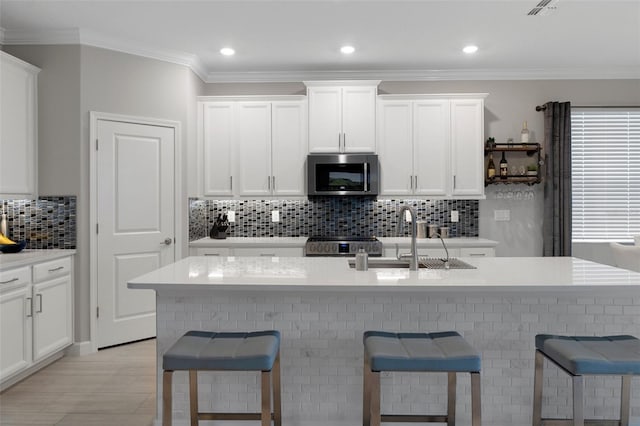 kitchen with a sink, stainless steel appliances, a kitchen bar, and white cabinetry