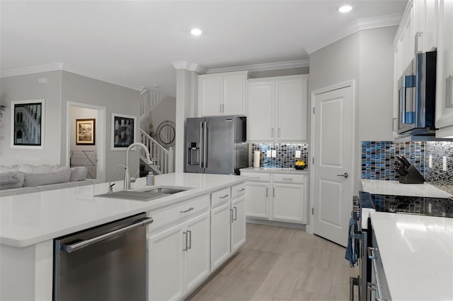 kitchen featuring a center island with sink, a sink, open floor plan, appliances with stainless steel finishes, and crown molding