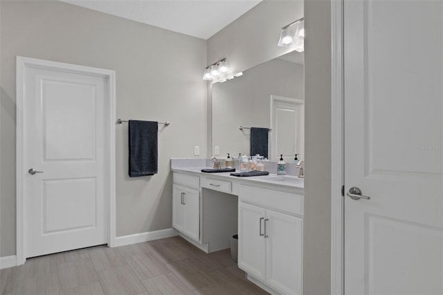 full bath with double vanity, baseboards, and a sink