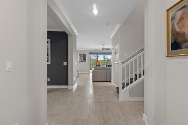 corridor featuring crown molding, stairway, and baseboards