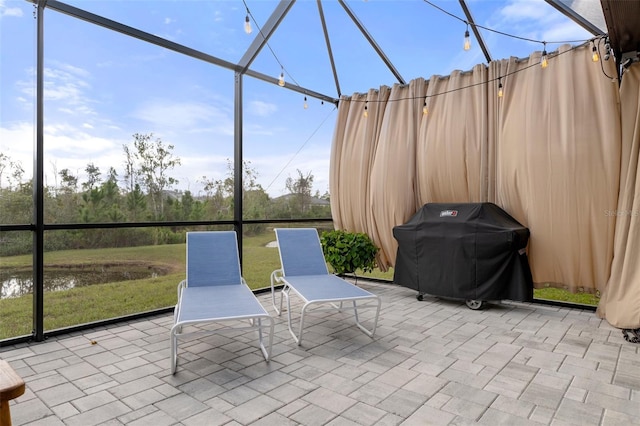 view of patio / terrace featuring glass enclosure and a grill