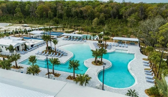 community pool featuring a forest view and a patio