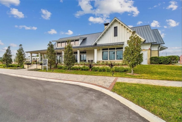 modern farmhouse with board and batten siding, a front lawn, a standing seam roof, and metal roof