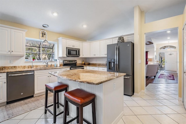 kitchen featuring appliances with stainless steel finishes, hanging light fixtures, white cabinets, a kitchen island, and light tile patterned flooring