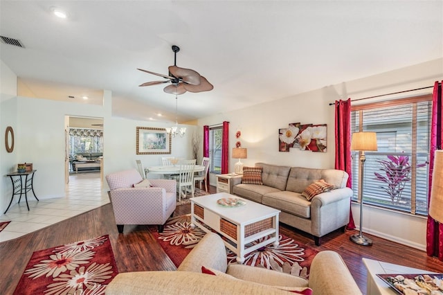 living room featuring ceiling fan with notable chandelier, wood-type flooring, and vaulted ceiling